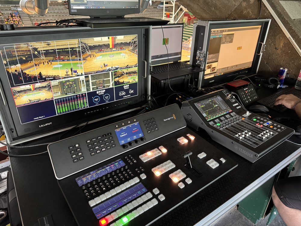 Bildmischer, Audiopult und Multiviewer mit Basketballspiel an einem Regieplatz in einer Sporthalle