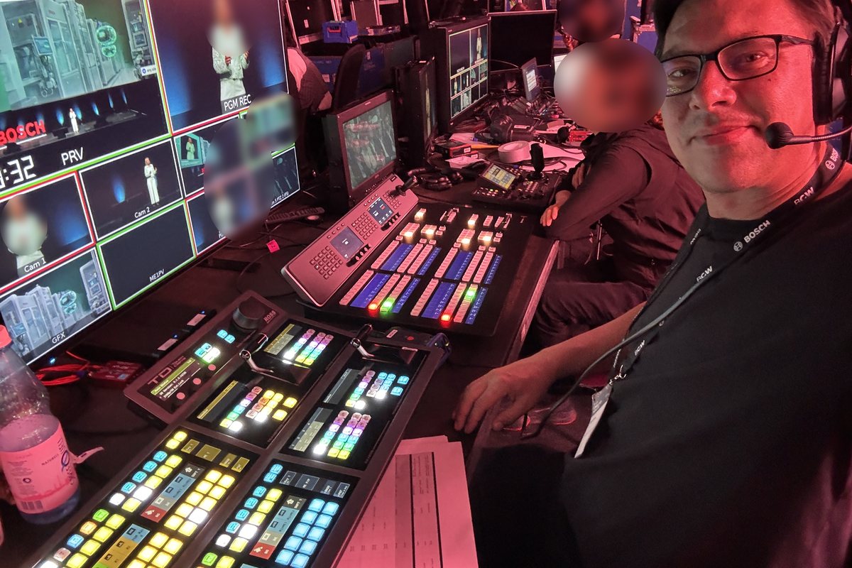 Nils Jahnke mit Headset am Bildmischerpult, daneben Multiviewer mit Bosch-Veranstaltung